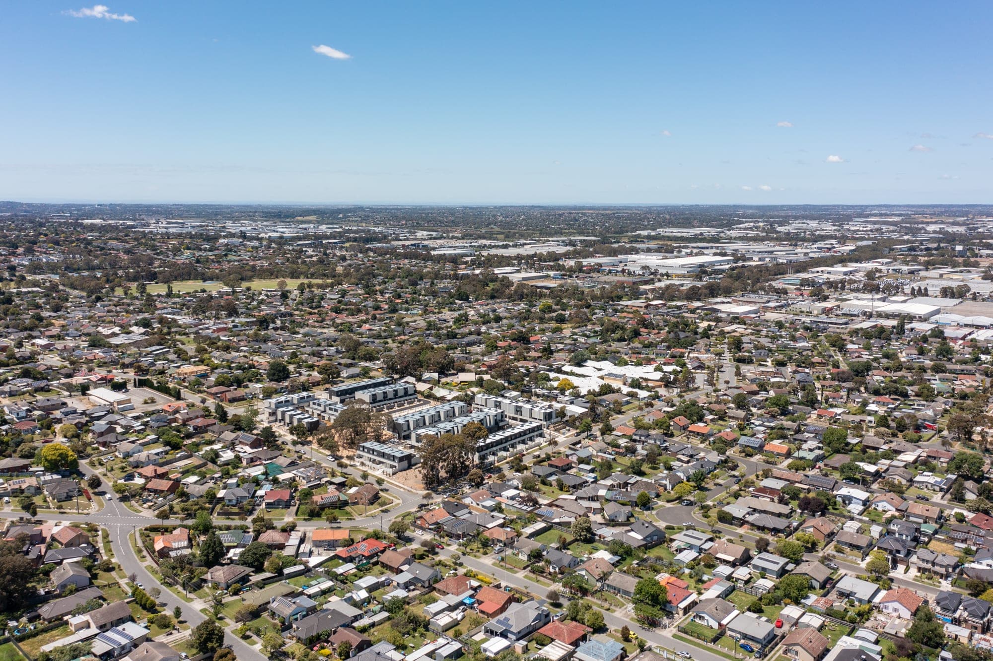 Drone view over Melbourne suburbs from a Kinsfolk rooftop, city skyline on the horizon